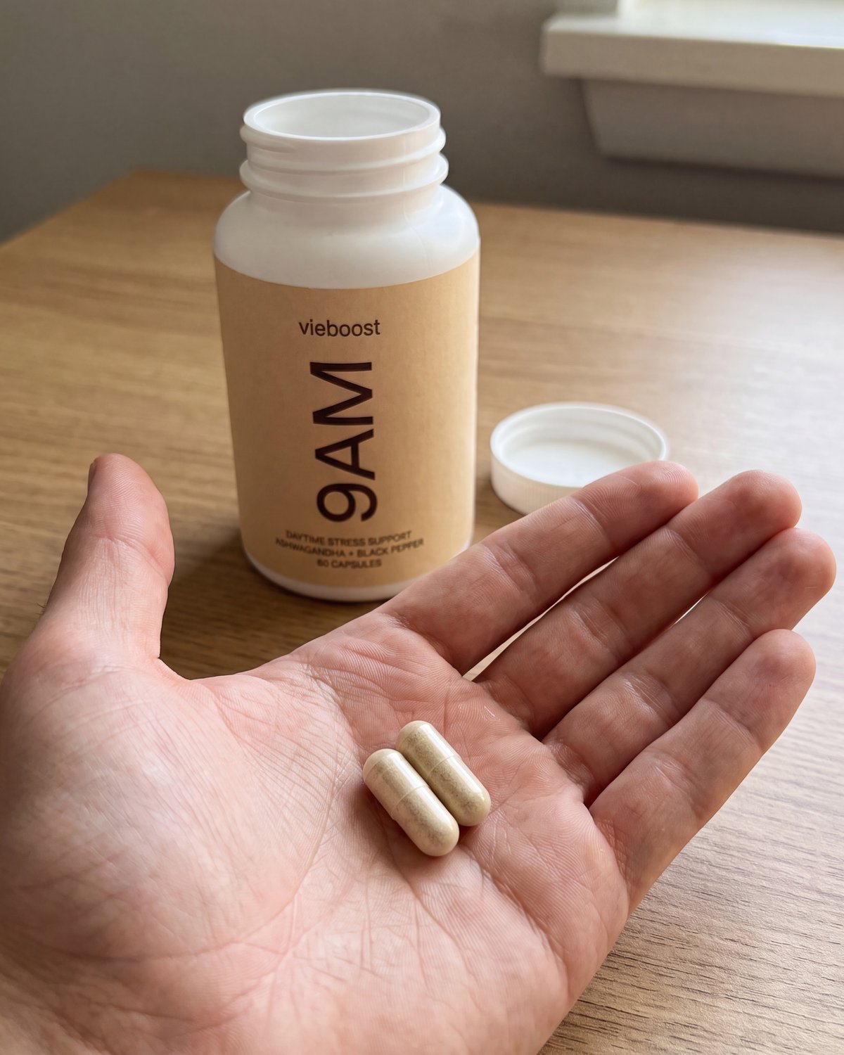 A single capsule beside a midday coffee — 9AM™ second dose
